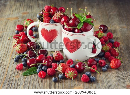 Ripe berries, cherries, raspberries, blueberries in cup, summer harvest. Fresh vitamins, vintage background
