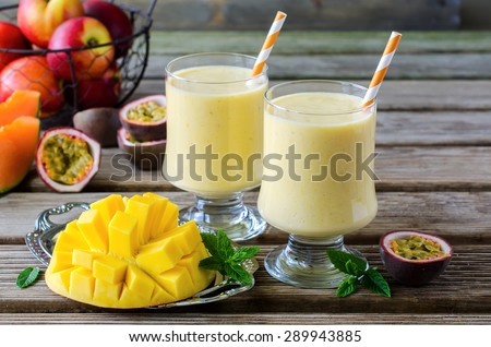 Healthy vitamin tropical mango and passion fruit smoothie with yogurt, milkshake, two glasses on wooden background