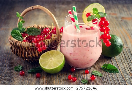 Healthy smoothie vitamins drink with red currant berries, mint and lime, shake with yogurt for breakfast on wooden rustic background, summer harvest, toned image