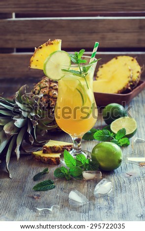 Cold refreshing pine apple cocktail drink with lime and mint for hot summer day, mojito idea, homemade lemonade with cubes of ice