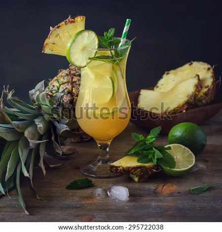 Cold refreshing pine apple cocktail drink with lime and mint for hot summer day, mojito idea, homemade lemonade with cubes of ice