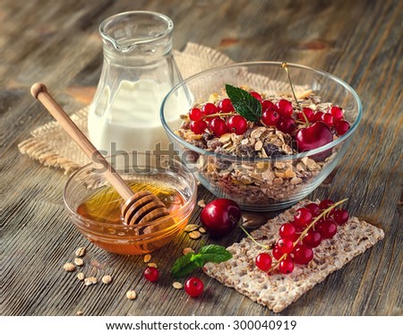 Healthy breakfast with muesli or granola, milk, fresh berries, red currant, whole-grain crispbread, honey. Rolled oats, morning cereals.