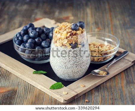 Healthy breakfast or morning snack with chia seeds pudding, granola, muesli and blueberries on wooden rustic background, vegetarian food, diet and health concept