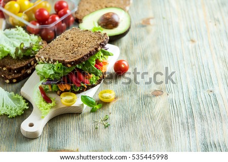 Vegan rye sandwich with fresh ingredients: avocado, salad, tomato, carrots, for healthy meal, vitamin and diet food