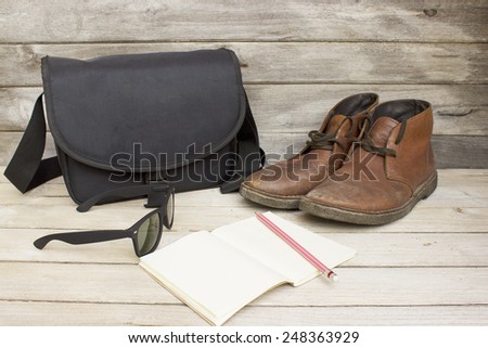 Travel journal,Still Life with bag,sunglasses,notebook,pencil and brown leather men\'s boots