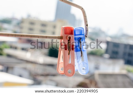 The old color plastic clothespin hanging on old clothes hanger with the town background
