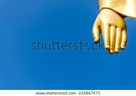 Hand gold Buddha on Blue sky Thai background.
