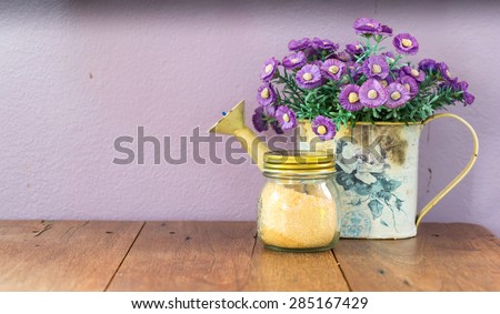 Artificial flowers in vase with sugar jar on wooden table with superior shadow vignette