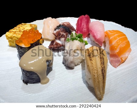 Sushi is authentic luxury delicious Japanese food, made from rice and raw fish, decorated on white dish isolated on black background
