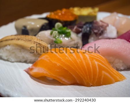 Sushi is authentic luxury delicious Japanese food, made from rice and raw fish, focus on the front raw salmon sushi, with blurring others behind