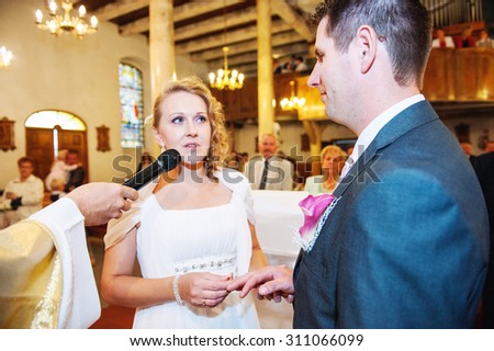 an image of the groom and the bride put on rings in the church