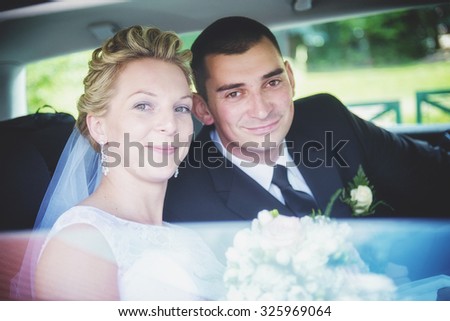 happy beautiful bride and groom sitting in the trunk of a car. Honeymoon, fun and laughter.