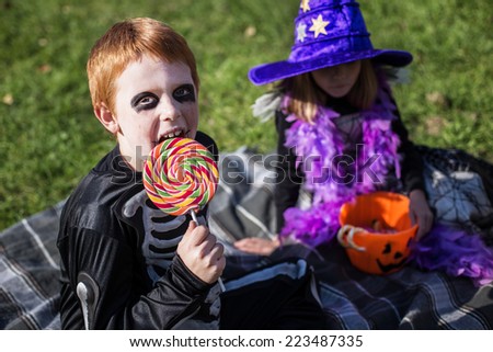 Boy and girl wearing halloween costume with candies. Witch. Skeleton. Outdoor portrait