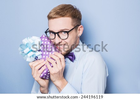 Guy holding a gift and emotionally happy. Present, birthday, Valentine. Studio portrait over blue background
