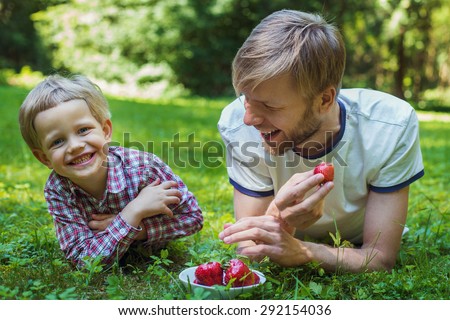 Summer photo happy father and son together lying on green grass. Life moment family resting on the nature