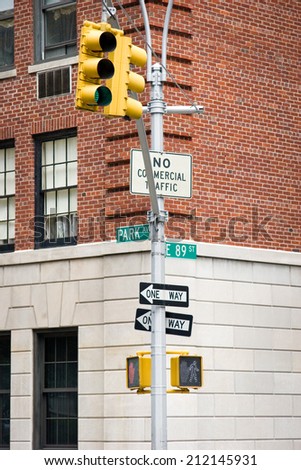 A street sign in Manhattan, New York City, with traffic lights, stop/walk signs and other signage for the location and traffic instructions.