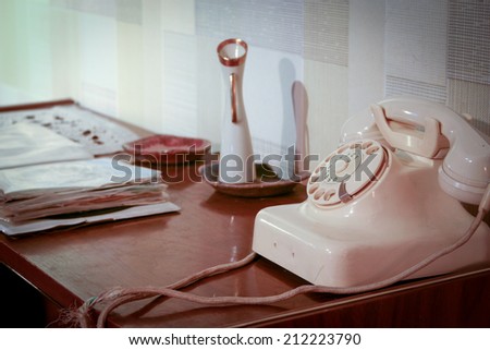 An retro scene of an old 1950\'s telephone in a contemporary setting with phone book on a side table.