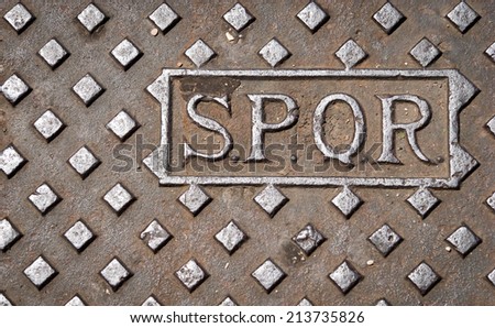 A manhole drain cover in Rome, Italy, with the letters SPQR.
