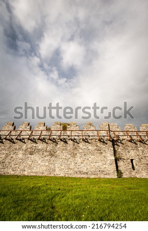 Detail of a traditional european castles fortifications in the form of battlements on top of a solid stone wall.