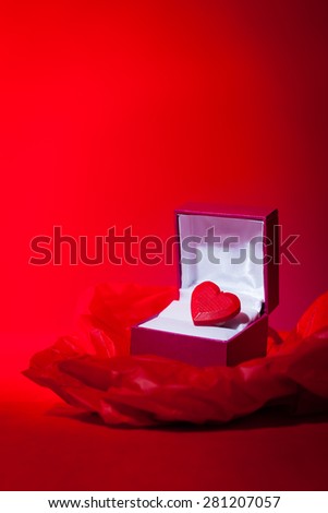 A most precious valentine themed still life image of a red love heart in a gift box.  Red background with copy space.