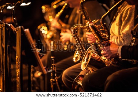 Big Band saxophone section. Candid view of a row of saxophone players in mid performance during a big band rehearsal.