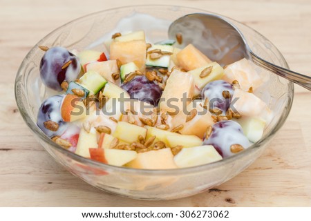 Fruits salad with plain low fat yogurt topping with sunflower seeds honey roasted.