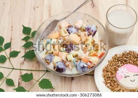 Fruits salad with plain low fat yogurt eat with cookie mom cartoon face with sunflower seeds honey roasted and a glass of soil milk.