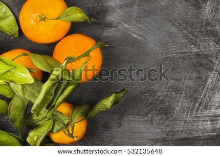 Tangerines with green leaflets on a dark background. Top view, copy space. Food background. Toning.