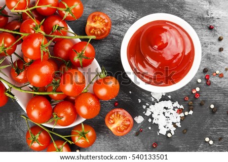 Tomato sauce in white bowl, spice and cherry tomatoes on a dark background. Tomato sauce in white bowl, spice and cherry tomatoes on a dark background. Top view. Food background.