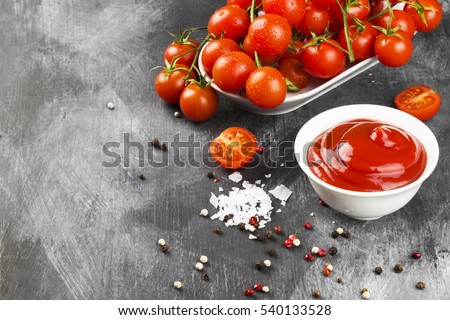 Tomato sauce in white bowl, spice and cherry tomatoes on a dark background. Copy space. Food background.
