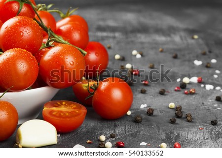 Cherry tomatoes on branch and spice on a dark background. Copy space. Food background.