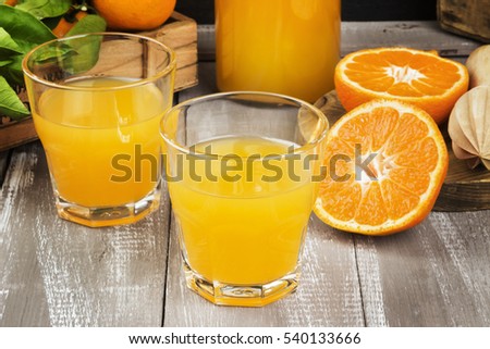 Tangerine juice in glass and fresh fruit on a wooden background. Toning.