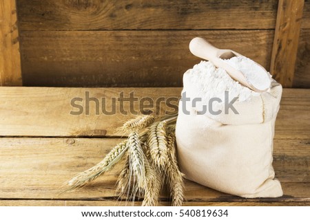 Flour in bag and wheat ears on a wooden background. Copy space. Food background.