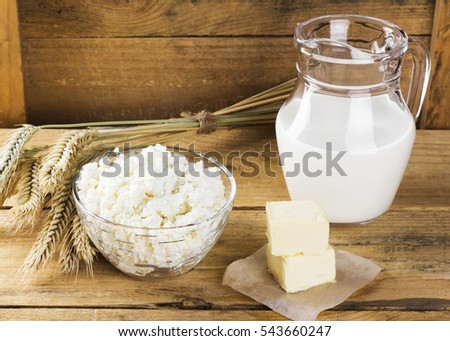Organic products: milk, cottage cheese, butter, wheat on a wooden background.