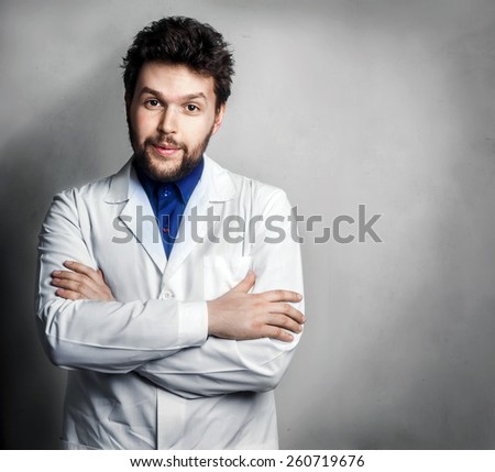 Confused doctor man posing with folded arms on grey background