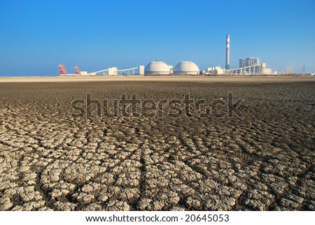 Cracks of the dried Seabed backgrounded by a power Plant