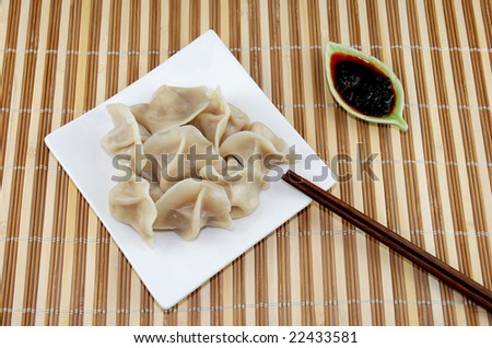 Plate of Dumplings with Spicy Sauce on Bamboo Pad