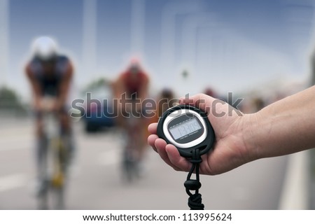 Timing of cyclists in bike race, close-up of hand and clock