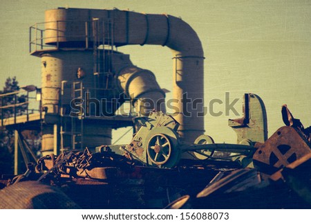 Machine behind the scrap heap works with fragmentation of the metal, aged and worn vintage style photo