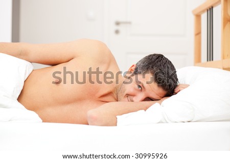 A caucasian beautiful man sleeping in a feather bed in sleeping room