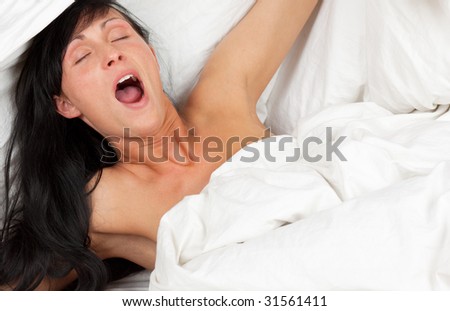 Tired woman with wided open mouth yawning in bed
