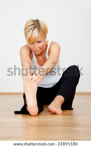Blond stretching spa woman at home sitting on wodden floor