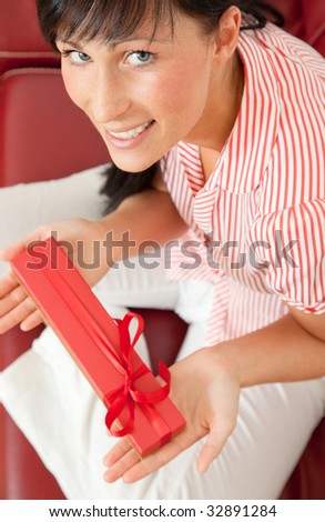 Smiling brunette woman holding a red box present and expressing positive for this sweet gift from her boyfriend