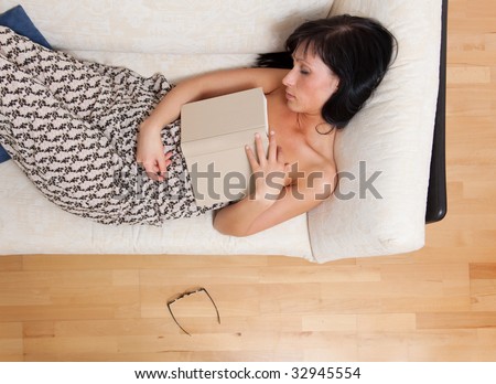 Tired woman with book laying on couch falling asleep closed eyes and glasses on floor