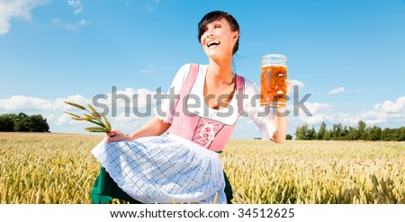 Funny oktoberfest beer holding woman with wheat in meadow cornfield