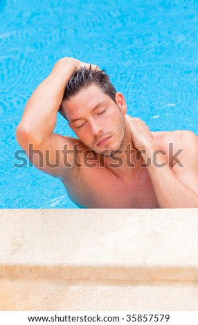 Cheerful good-looking wet hair man in the blue pool relaxing