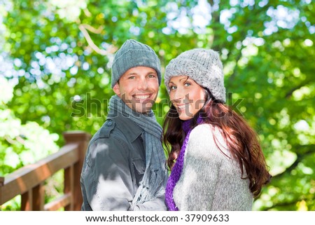 Happy natural walking couple in forest park wearing winter clothes