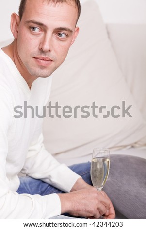 Lonely man relaxing alone at home drinking glass champagne on couch