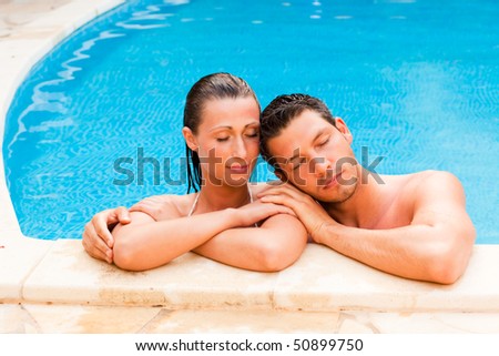 Relaxing summer wet couple in blue swimming pool