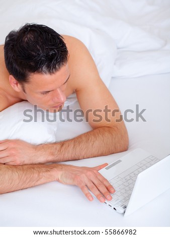 Bed lying web browsing man with notebook on sunday morning